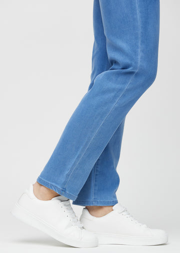 Regular jeans for women in blue, color Geraniums. Close-up at the ankles on a model, showing the straight leg openings.