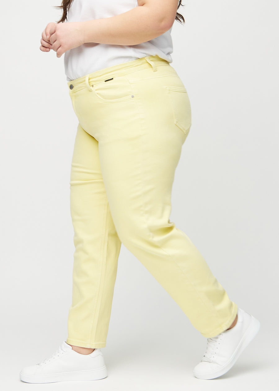 Light yellow regular jeans seen from the side on a plus-size model.