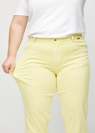 The plus-size model stretches the jeans at the thigh to show the stretch.