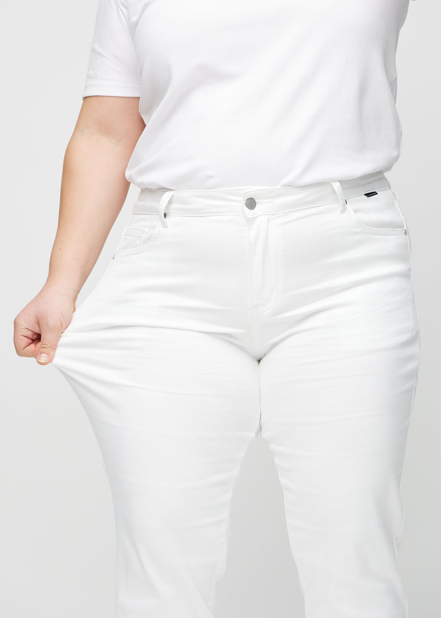 Regular jeans for women in white, color Marguerites. A plus-size model stretches the fabric at the thigh to show its stretch.