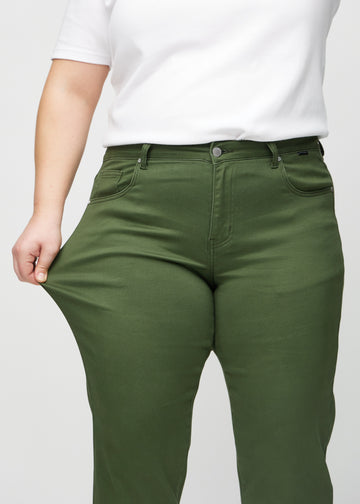 Regular jeans for women in dark green, color Renewals. A plus-size model stretches the fabric at the thigh to show its stretch.