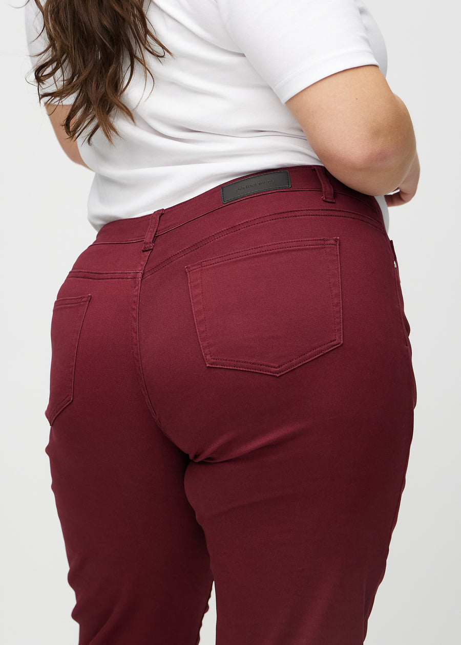 Regular jeans for women in dark red, color Santas. Close-up from behind on a plus-size model, showing fit and details.