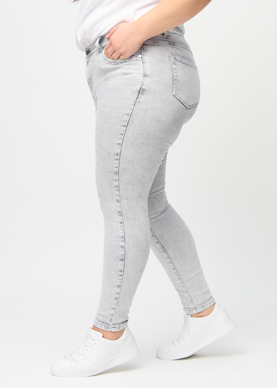 Skinny jeans for women in light grey, color Ashes. Side view on a plus-size model.