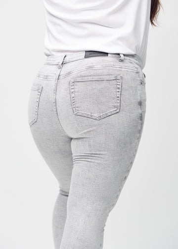 Skinny jeans for women in light grey, color Ashes. Close-up back view on a plus-size model, showing details.