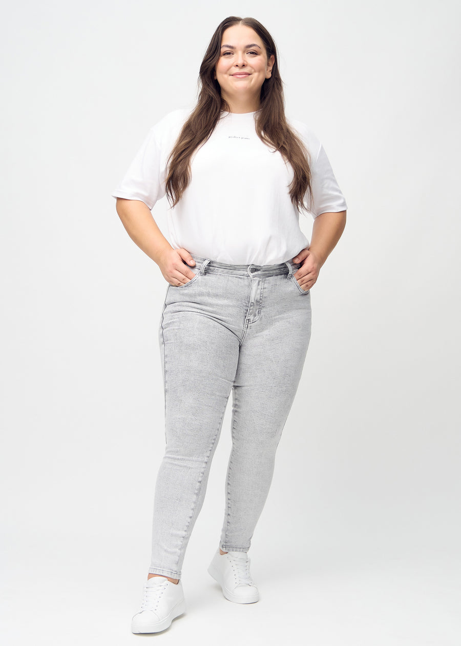 Skinny jeans for women in light grey, color Ashes. Full-length view of a plus-size model in the jeans.