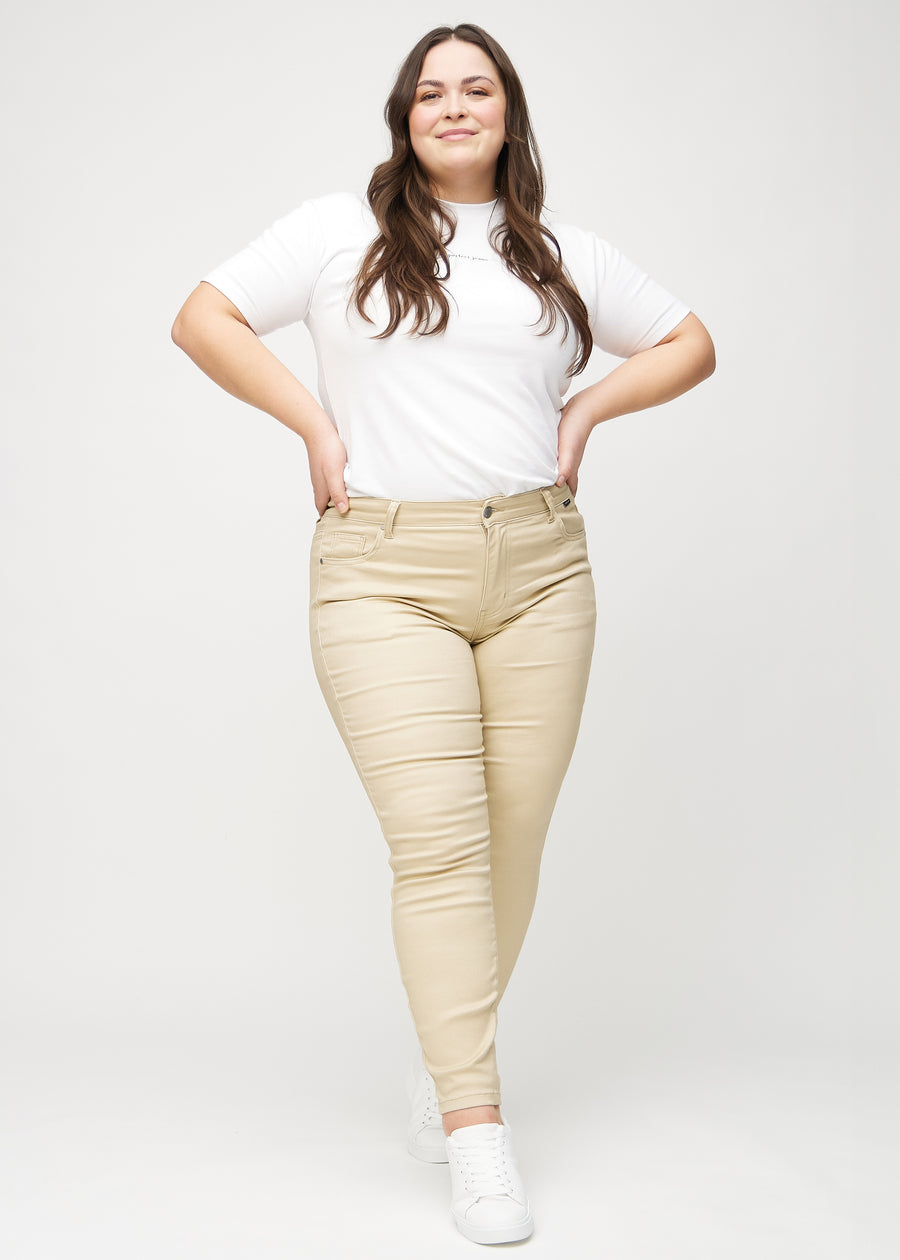 Full image of a plus-size model in beige skinny jeans.