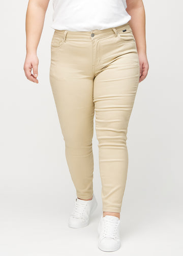 Beige skinny jeans, model name Gazelles, which fits closely to the leg on a plus-size model, seen from the front.