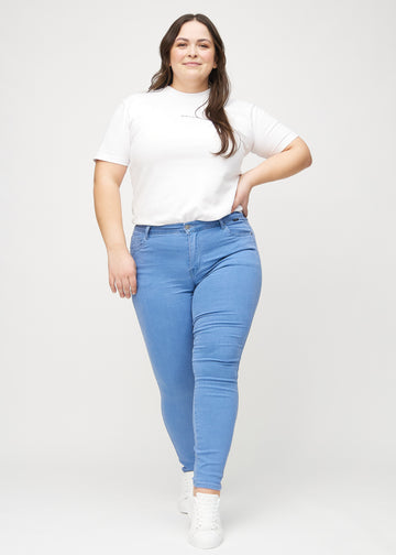 Skinny jeans for women in blue, color Geraniums. Full-length view of a plus-size model wearing the jeans.