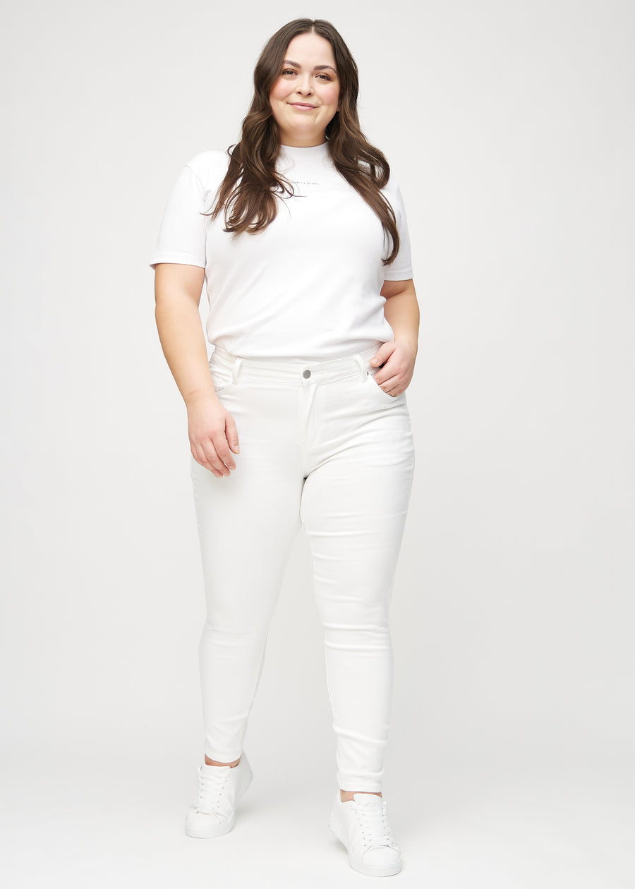 Full image of a plus-size model in white skinny jeans.