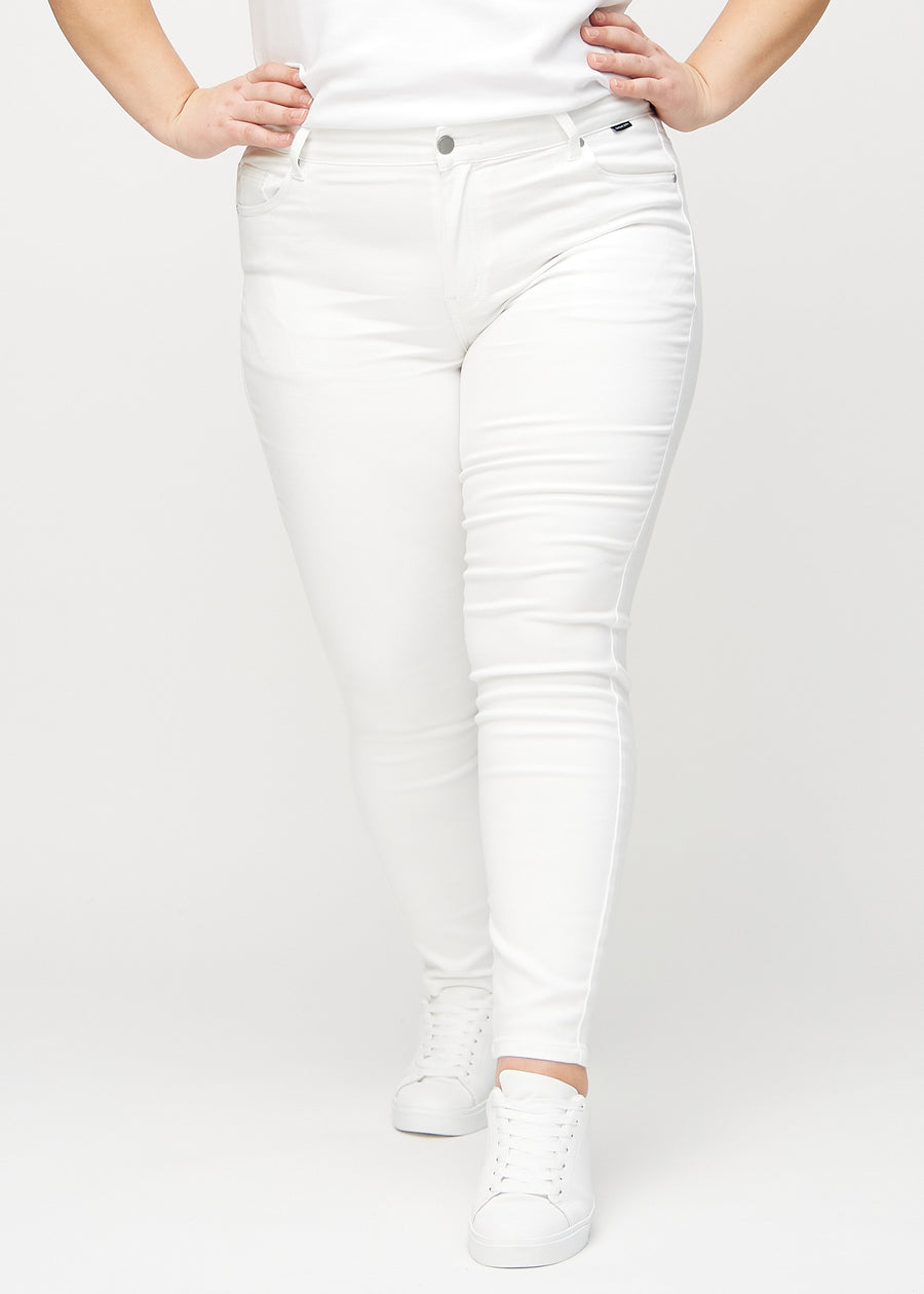 White skinny jeans, model name Marguerites, which fit closely to the leg on a plus-size model, seen from the front.