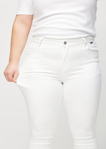 The plus-size model stretches the jeans at the thigh to show the stretch.