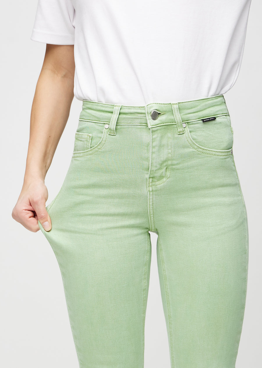 Skinny jeans for women in light green, color Mints. A model stretches the jeans at the thigh to show the fabric&