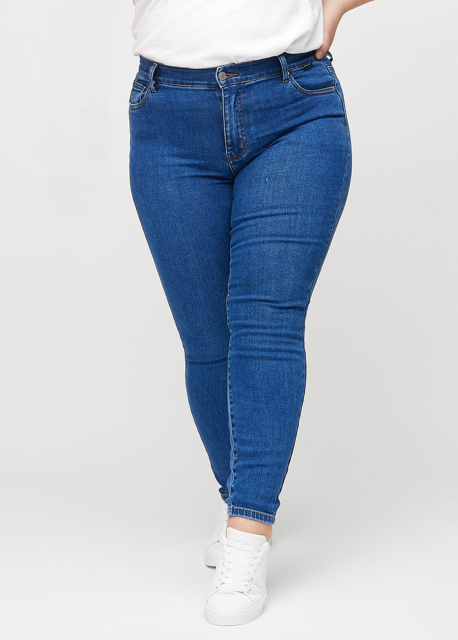 Skinny jeans for women in dark blue, color Oceans. Front view on a plus-size model, showing the close fit through the legs.