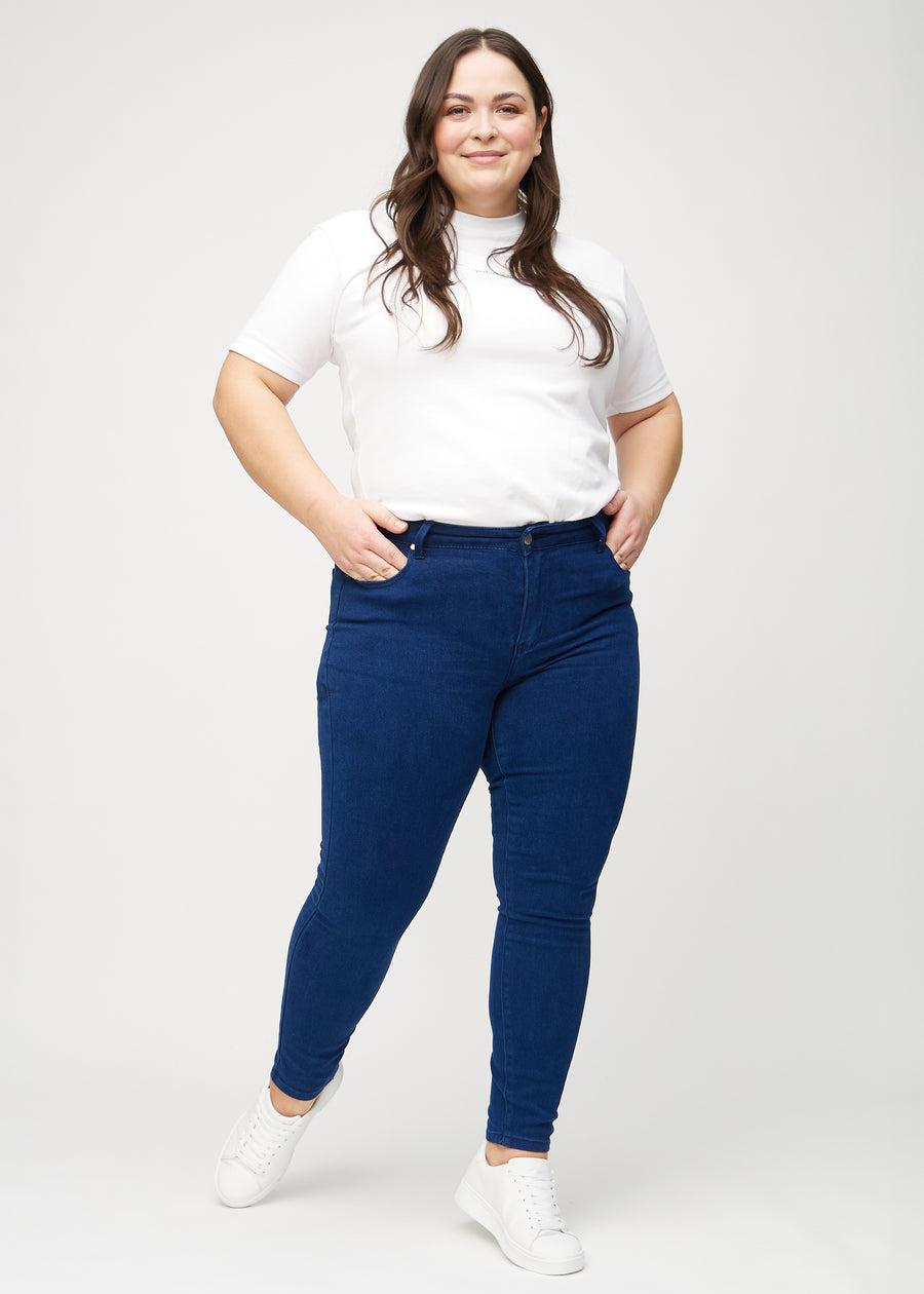 Full image of a plus-size model in dark blue skinny jeans.