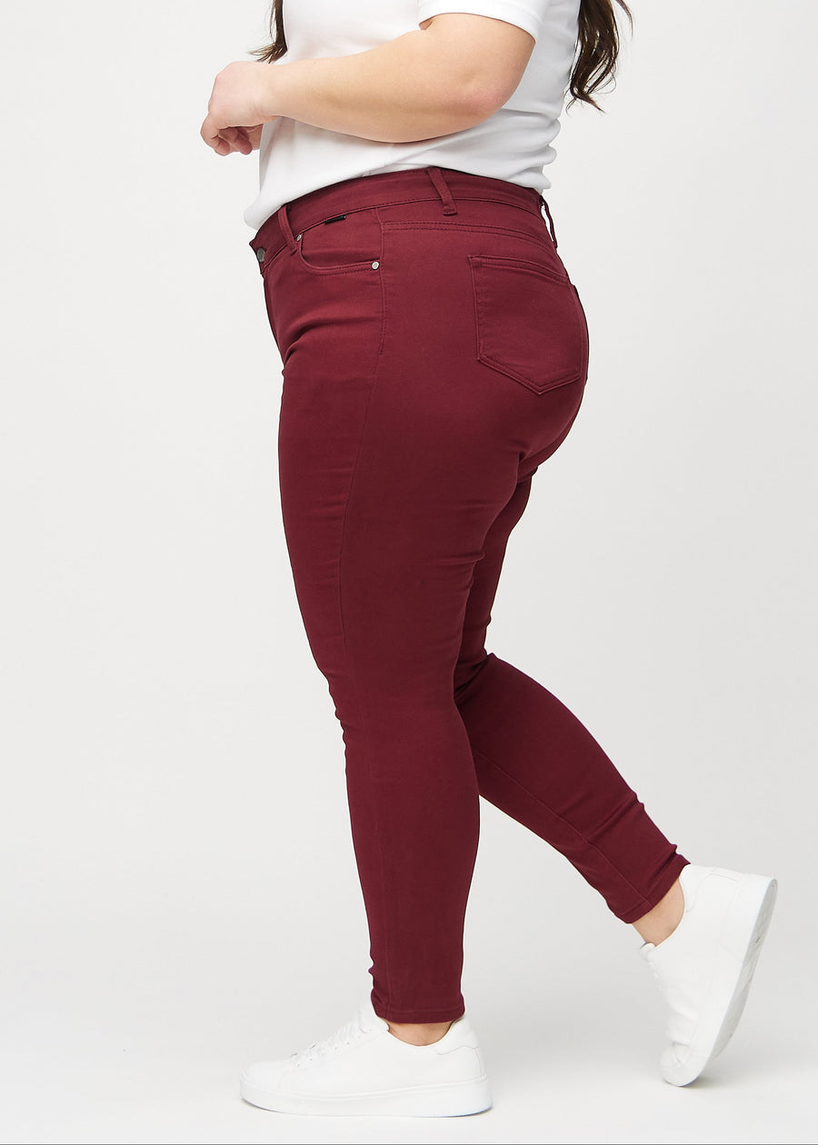Dark red skinny jeans seen from the side on a plus-size model.