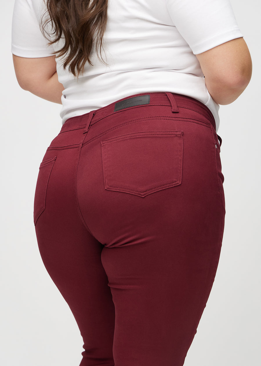 Dark red skinny jeans seen from the back close up on a plus-size model to show details.