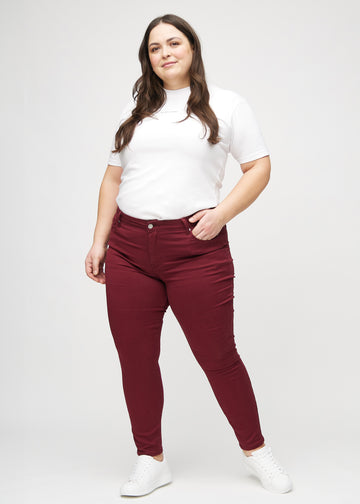 Full image of a plus-size model in dark red skinny jeans.