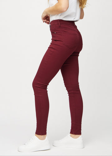 Dark red skinny jeans seen from the side on the model.