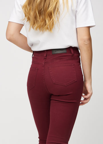 Dark red skinny jeans seen from the back close up to show details.