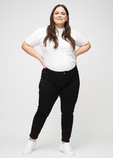 Slim jeans for women in black, color Ravens. Full-length view of a plus-size model wearing the jeans.