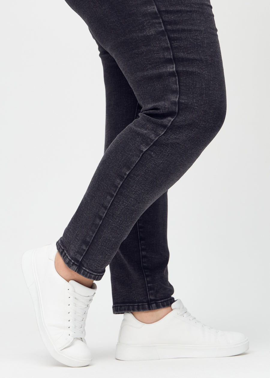Slim jeans for women in dark grey, color Shadows. Close-up at the ankles on a plus-size model, showing the fit at the leg openings.