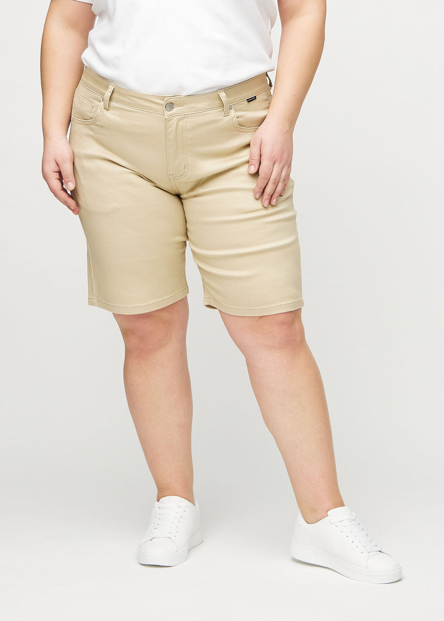 Beige regular middle shorts, model name Gazelles, which go straight down the leg and end just above the knee on a plus-size model, seen from the front.