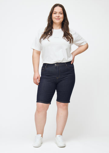 Full image of a plus-size model wearing deep dark blue denim shorts for women in the colour Midnights with a skinny fit.