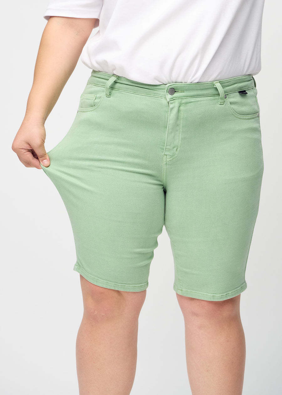 The plus-size model stretches the shorts at the thigh to show the stretch.
