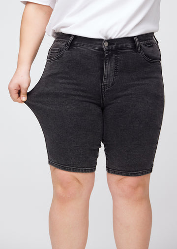 Plus-size model stretches the shorts at the thigh to show the stretch.