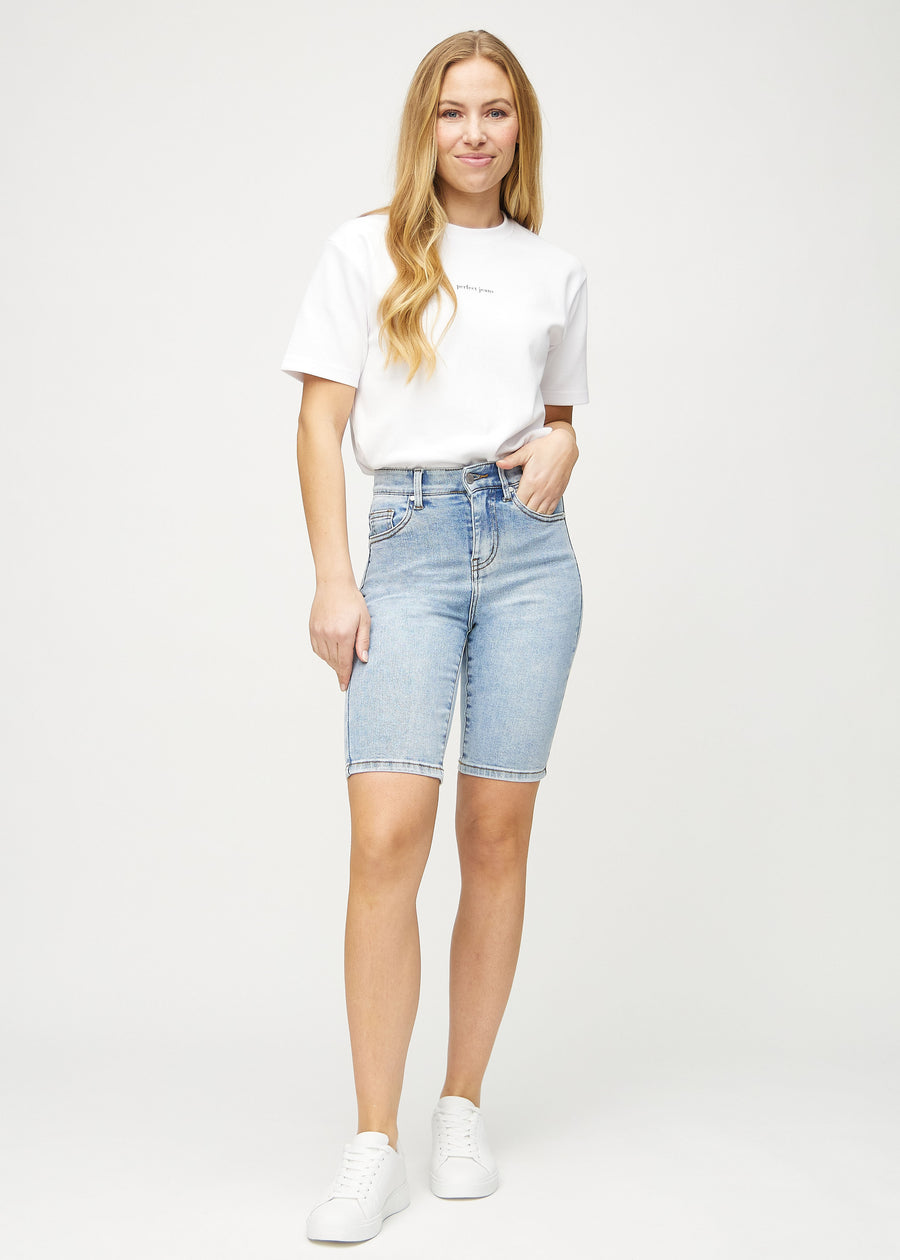 Full image of model in light denim skinny middle shorts.