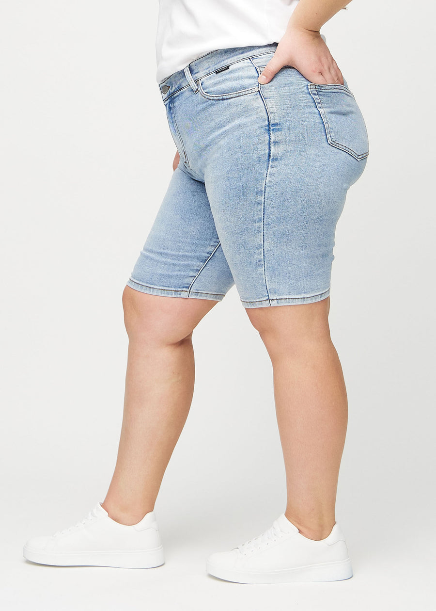 Light denim skinny middle shorts seen from the side on a plus-size model.