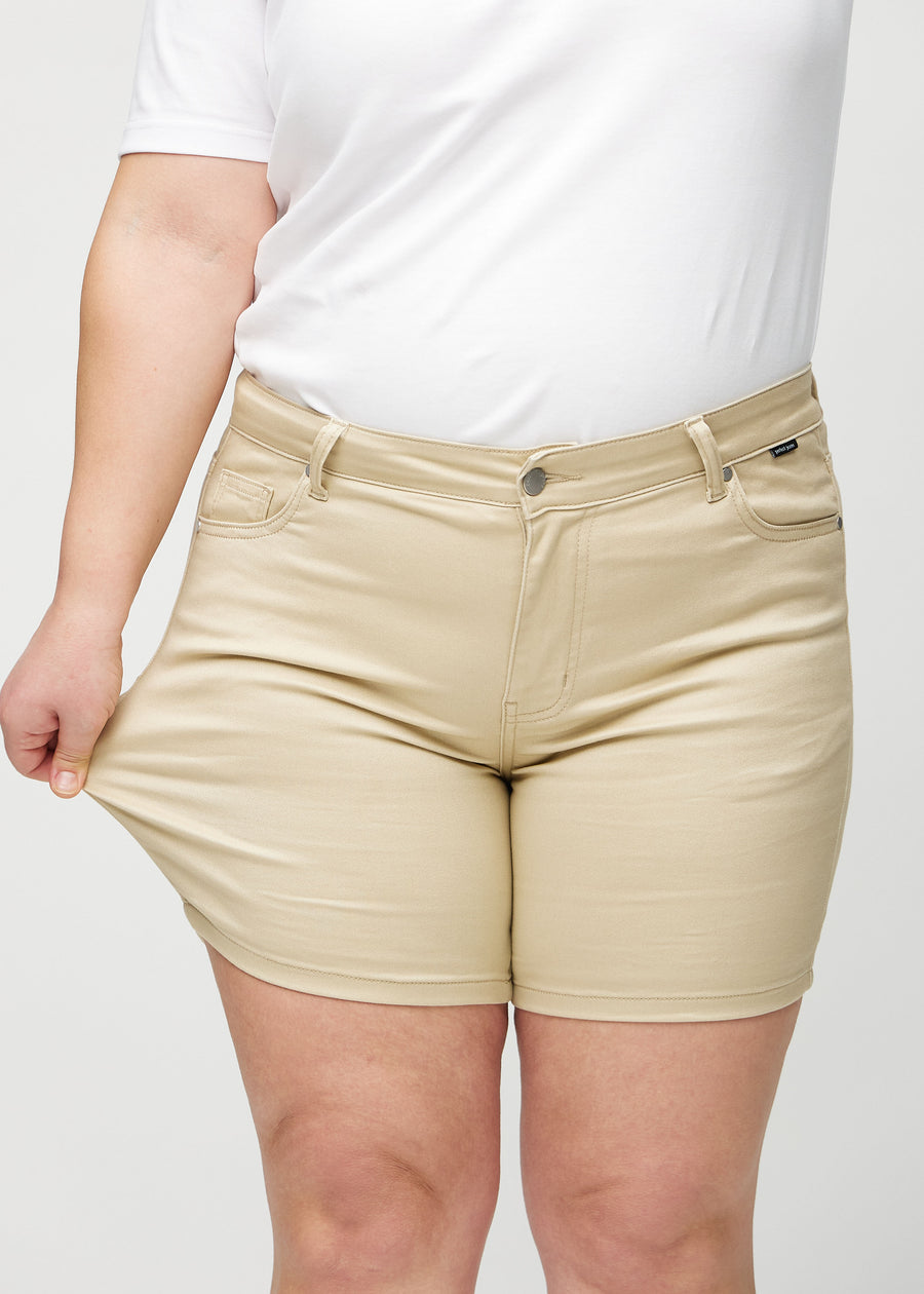 The plus-size model stretches the shorts at the thigh to show the stretch.