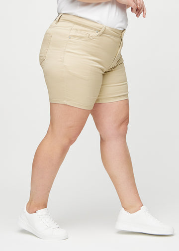 Beige skinny short shorts seen from the side on a plus-size model.