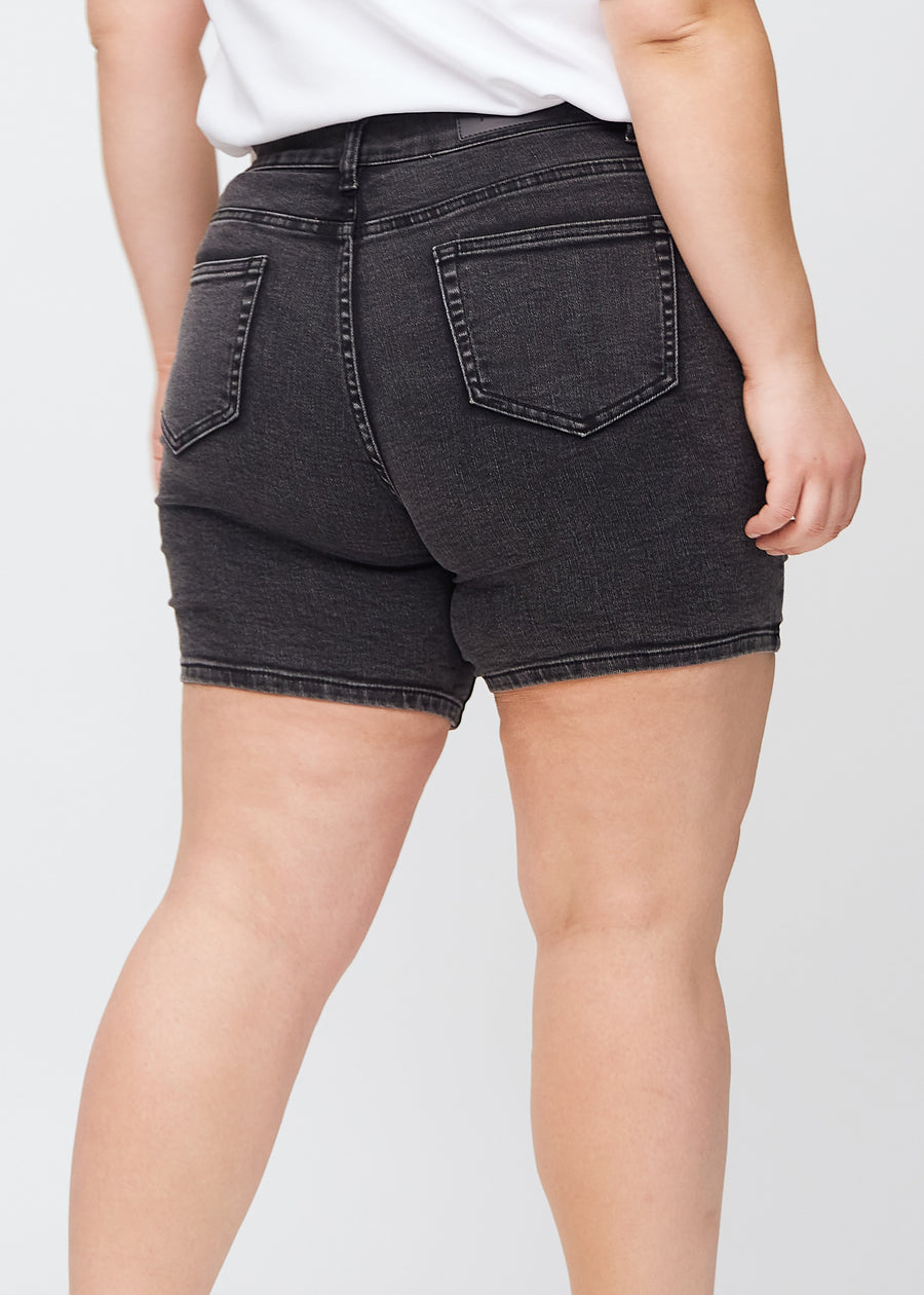 Dark grey denim skinny short shorts seen from the back close up on a plus-size model to show details.