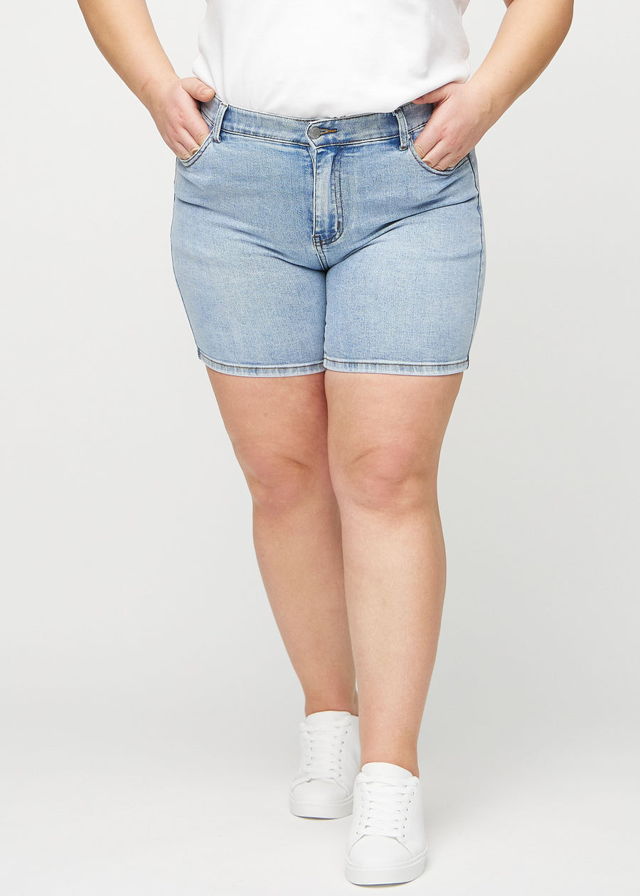 Light denim skinny short shorts, model name Waves, which fit tightly and end mid-thigh on a plus-size model, seen from the front.