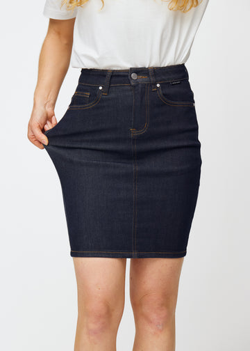 Model stretches deep dark blue denim skirt for women in the colour Midnights at the thigh to show the material’s stretch.