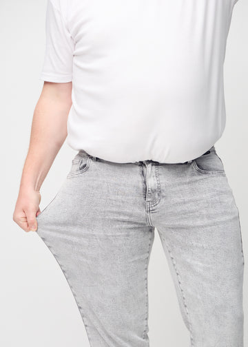 The plus-size model stretches the jeans at the thigh to show the stretch.