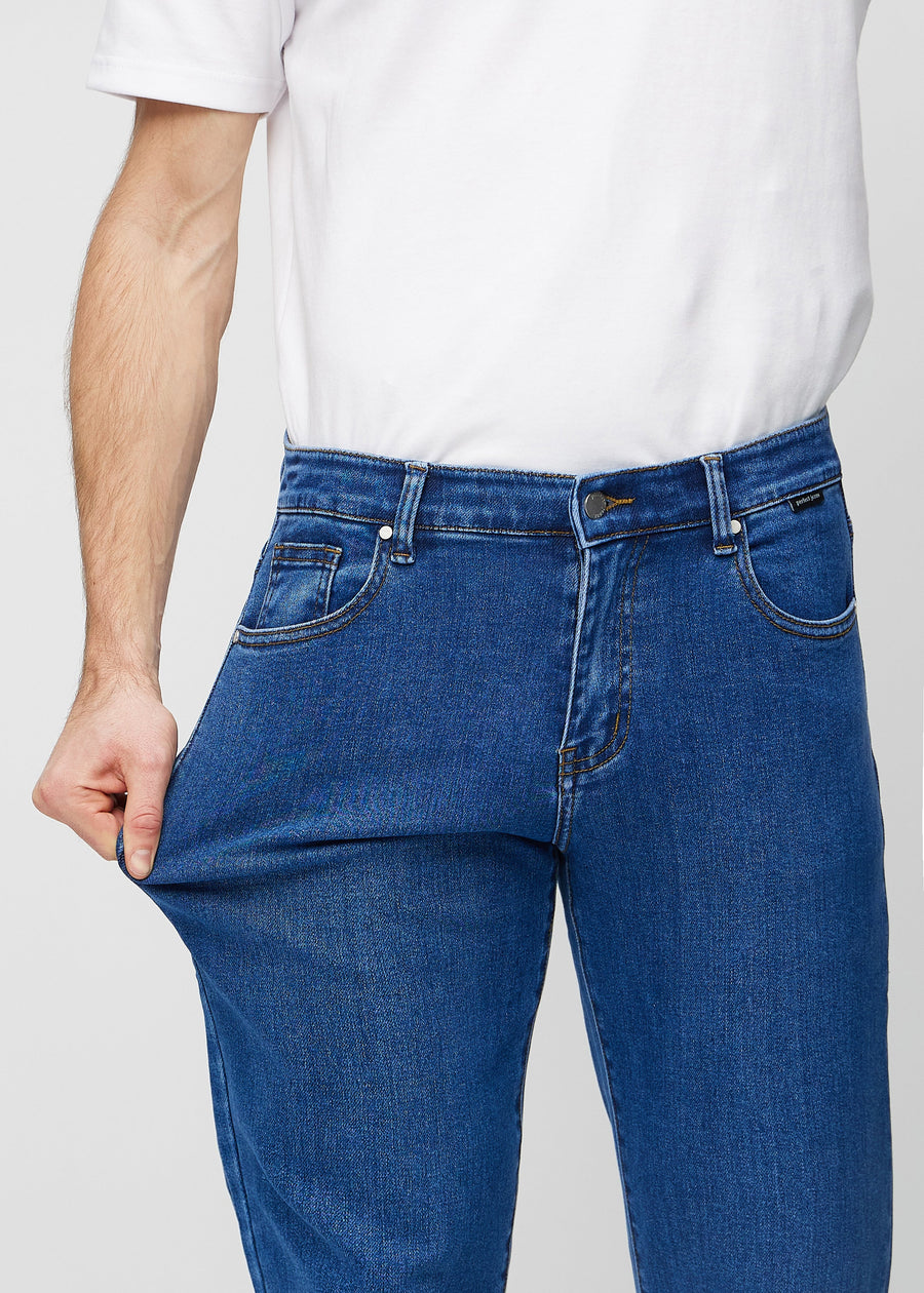 The model stretches the jeans at the thigh to show the stretch.