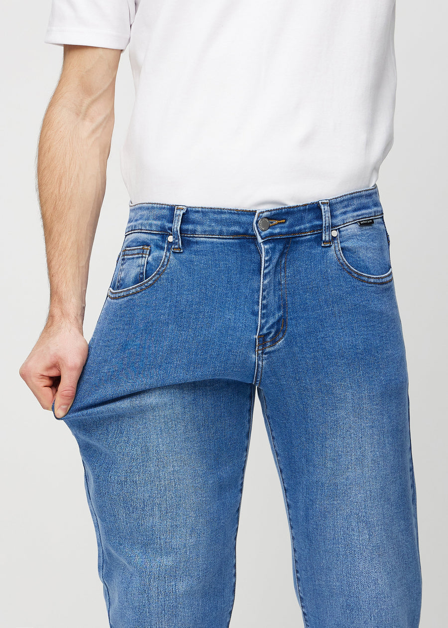 The model stretches the jeans at the thigh to show the stretch.