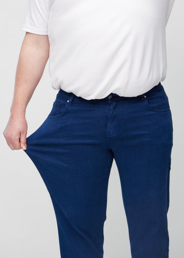 The plus-size model stretches the jeans at the thigh to show the stretch.
