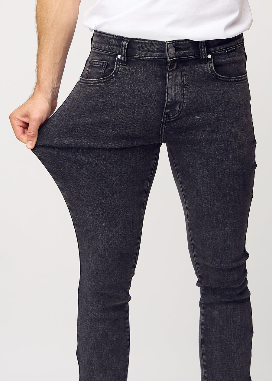 Model stretches the jeans at the thigh to show the fabric&