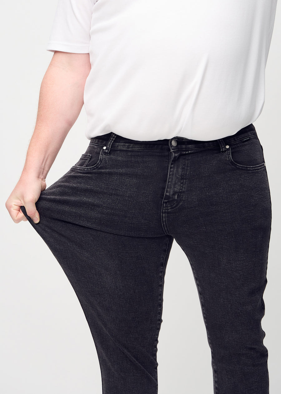 Plus-size model stretches the jeans at the thigh to show the fabric&