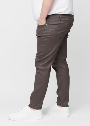 Grey-brown slim jeans viewed from the side on a plus-size model.
