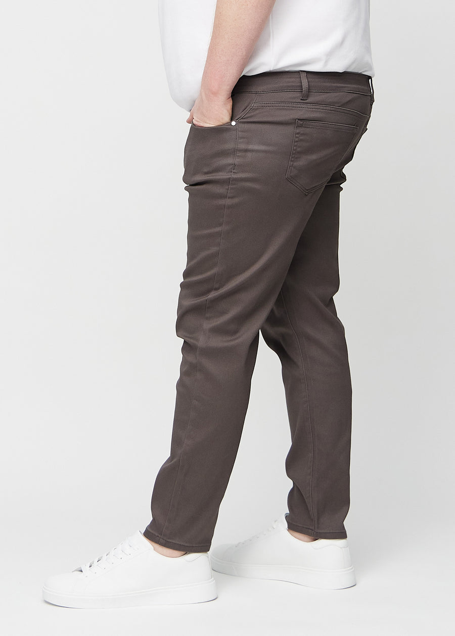 Grey-brown slim jeans viewed from the side on a plus-size model.