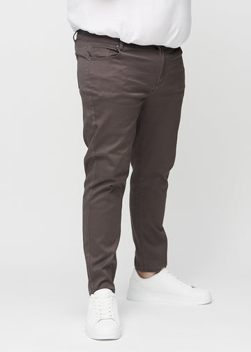 Grey-brown slim jeans, model name Thunders, fitted closely along the legs on a plus-size model, front view.