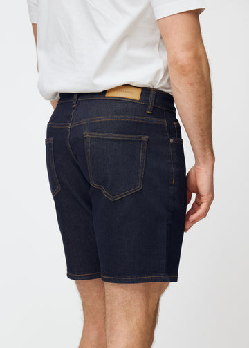 deep dark blue denim shorts for men in the colour midnights seen from the back in close-up to show fit and details.