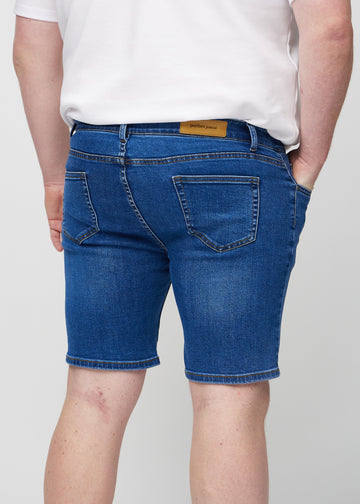 Dark denim middle-slim shorts seen from the back close up on a plus-size model to show details.