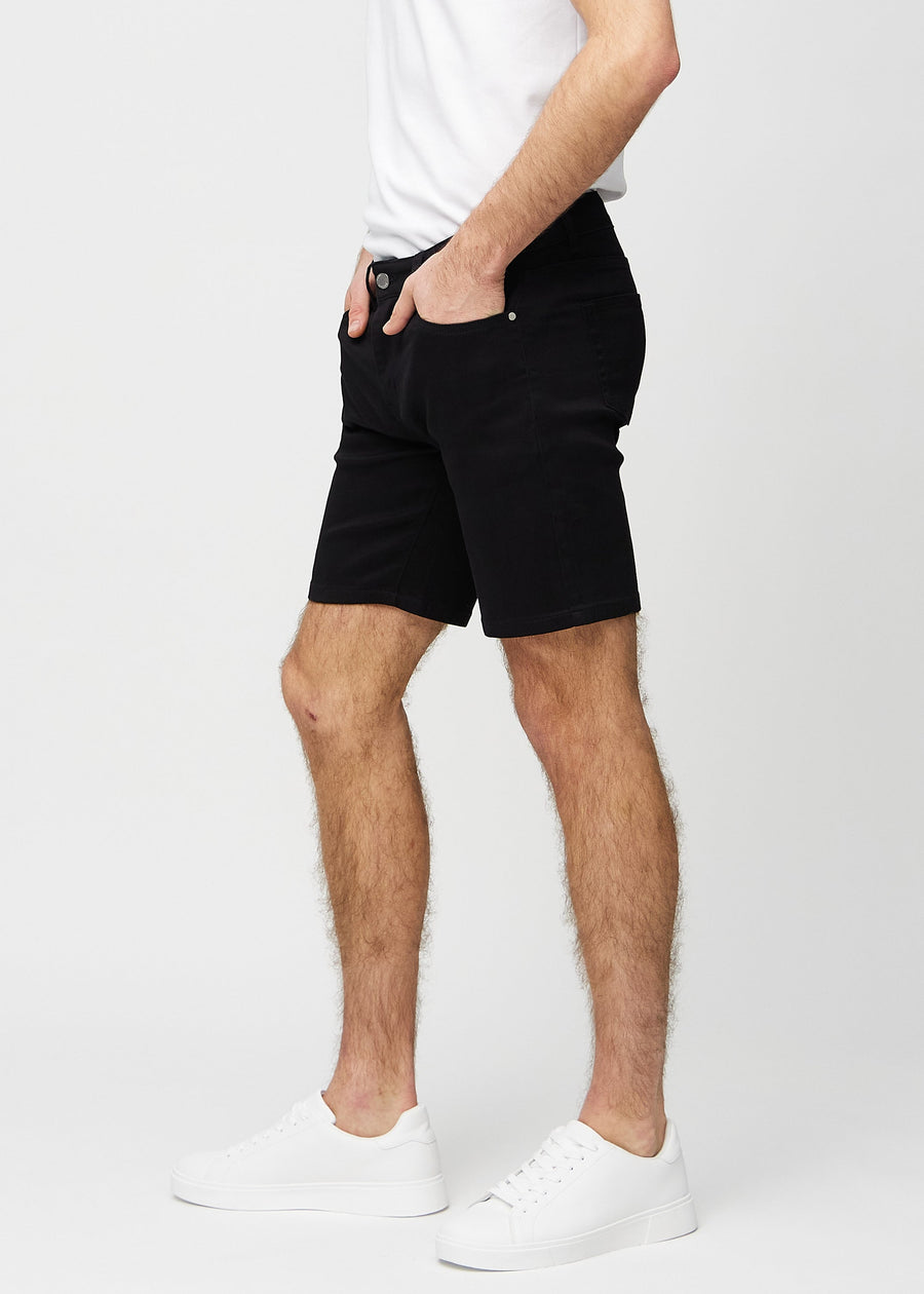 Black middle-slim shorts seen from the side on a model.