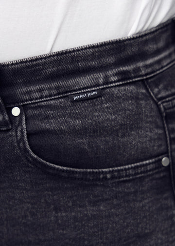 Forlommen på et par mørkegrå denim slim jeans, hvor man kan se logoet på en plus-size model.