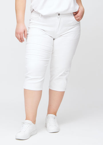 Hvide slim capris, farve Marguerites, med tætsiddende pasform og længde lige under knæet – set forfra på plus-size model.